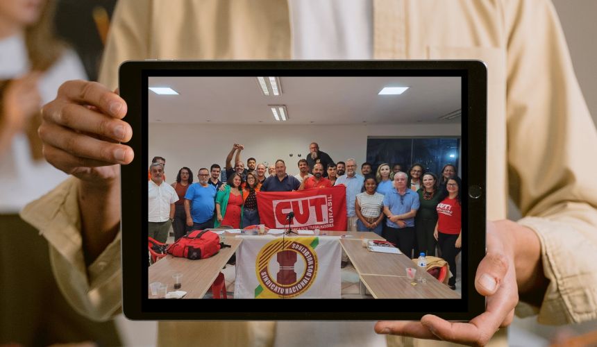 Um homem segurando um tablet. No meio, a foto de representantes de todos os sindicatos das estatais.