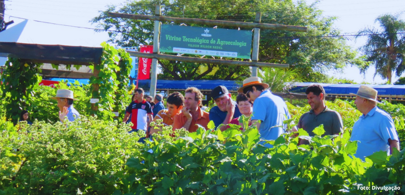 faixada da Vitrine de Agroecologia. Na frente várias pessoas e temos muitas plantações verdes.