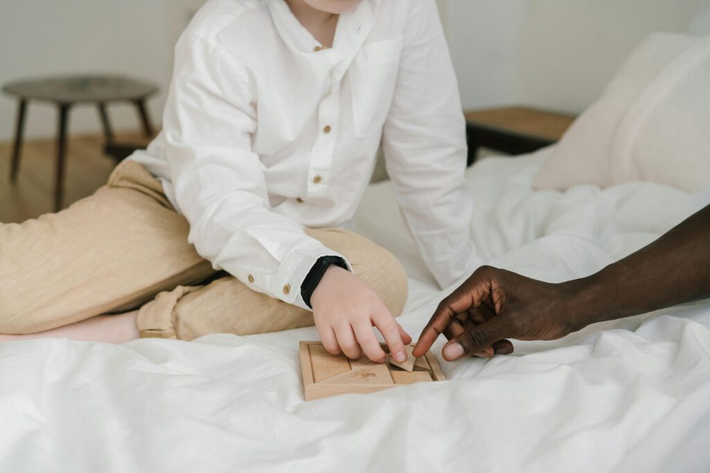 menino fazendo terapia jogando. Aparece as mãos dele e do terapeuta que é preto. O menino é branco. 