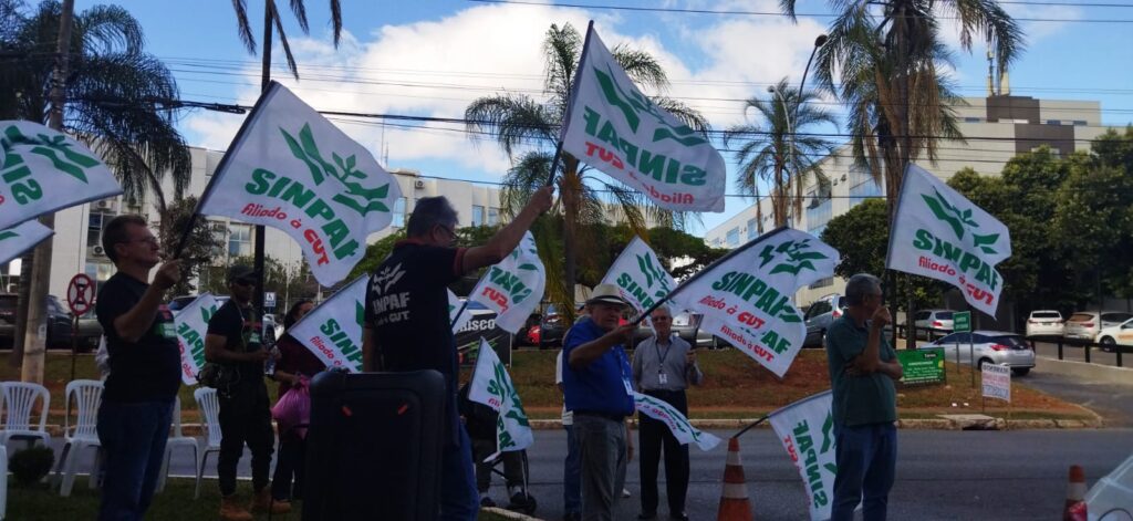 Trabalhadores segurando as bandeiras do SINPAF. 