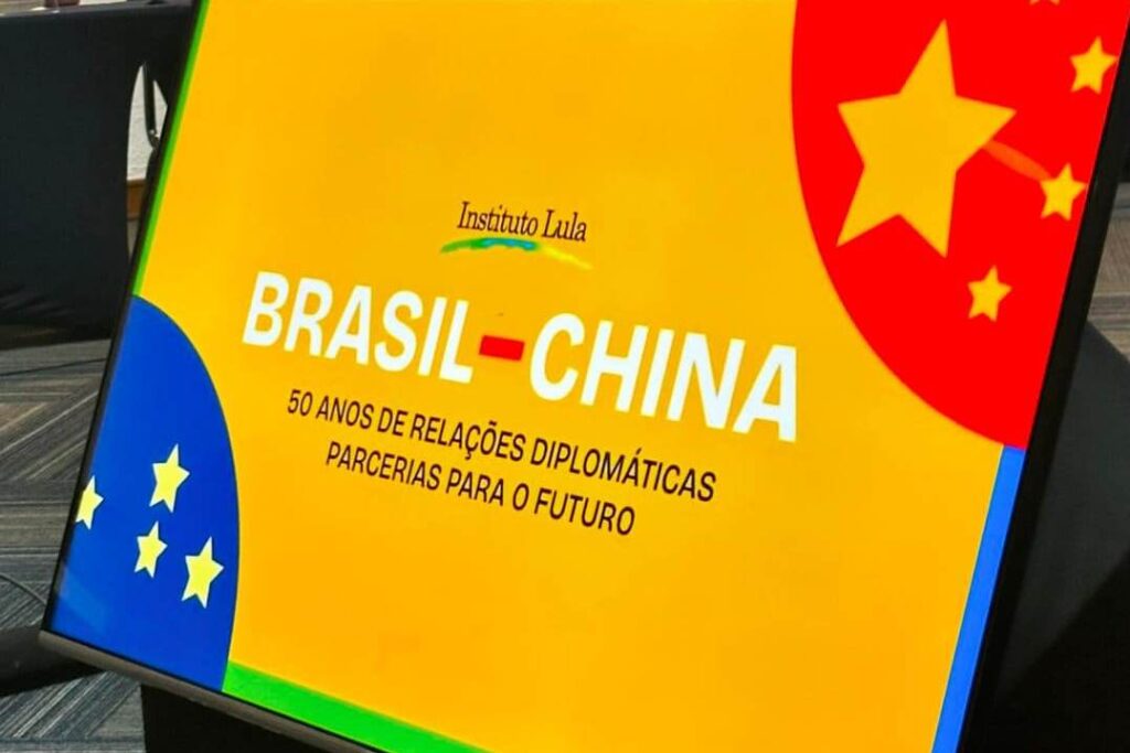 Arte com fundo amarelo. Está escrito Brasil-China - 50 anos de relações diplomáticas parcerias para o funturo. Do lado direito superior parte do mapa da China que ficam as estrelas. Do lado esquerdo inferior parte do mapa do Brasil com as estrelas. 