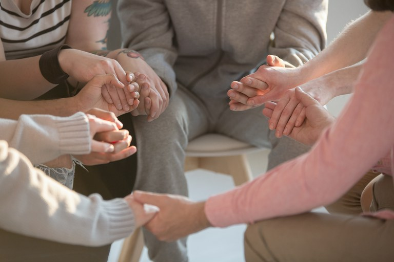 várias pessoas de mãos dadas em círculo. 