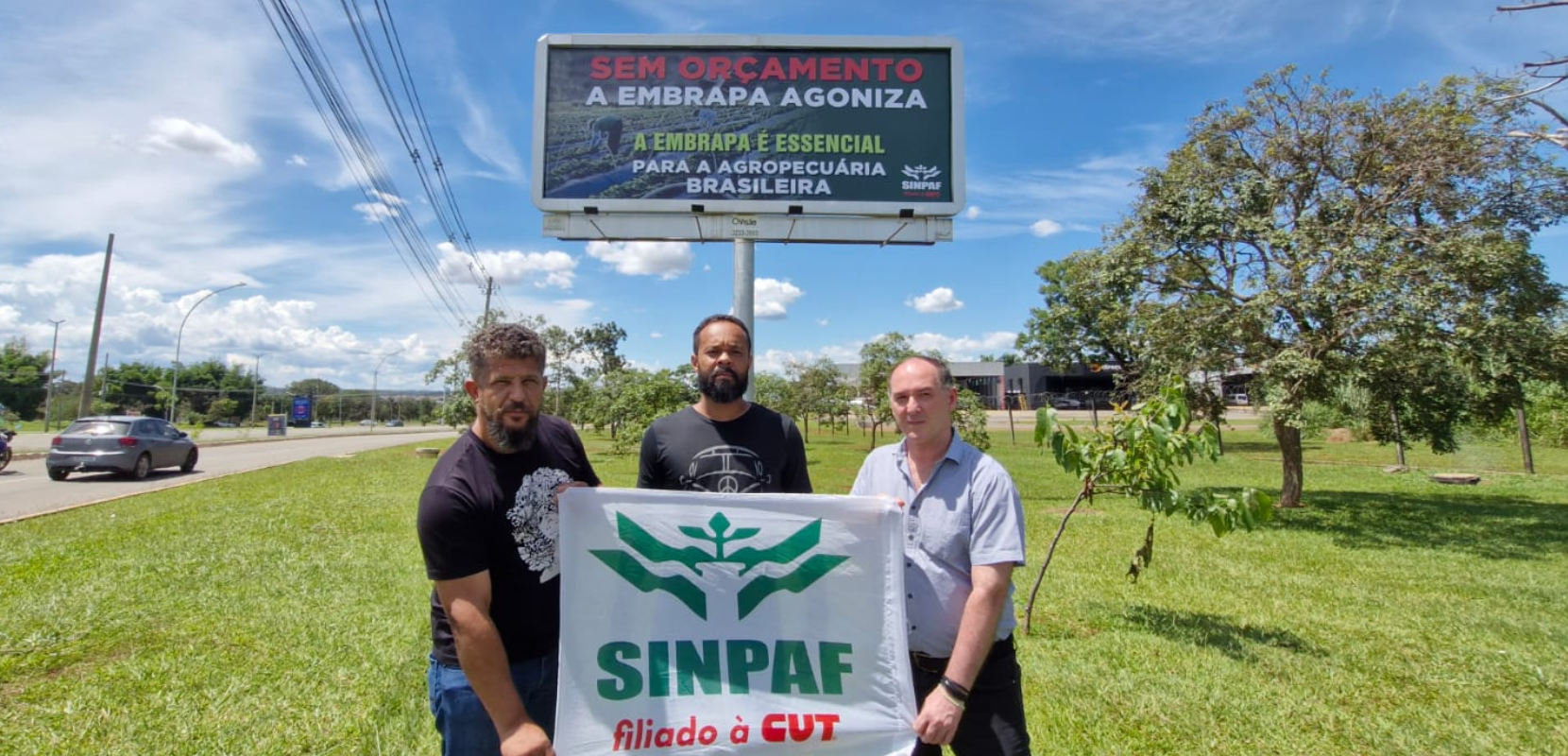 outdoor em brasilia e os três diretores com a bandeira do sinpaf